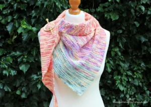 Stunning crochet triangle shawl made with Caron Big Cakes self-striping yarn, featuring seamless gradient color transitions in vibrant festival tones – perfect one-cake project for 2026